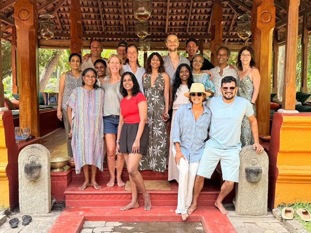 A group of retreat guests on the red steps of a carved wooden pavilion